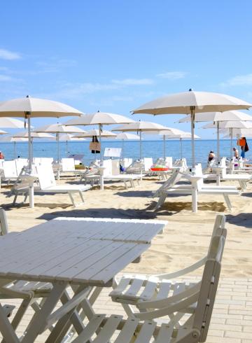 Sunny beach, white umbrellas, relaxation, and calm sea on the horizon.