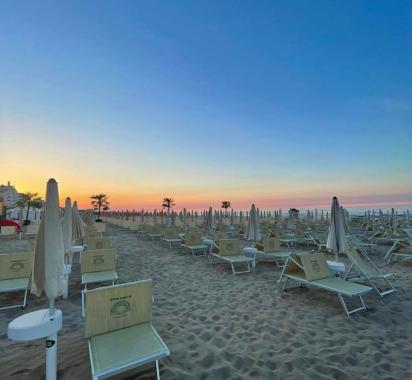Spiaggia deserta al tramonto con ombrelloni chiusi.