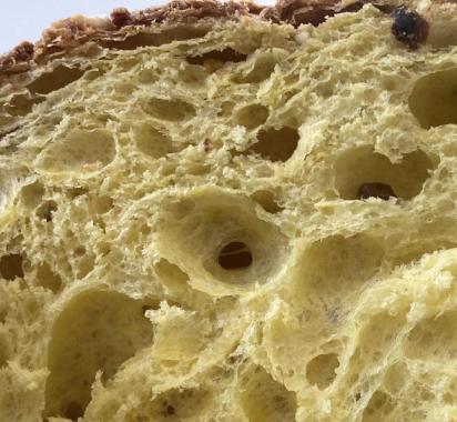 Fetta di panettone con alveolatura soffice e dorata, tipica del dolce natalizio italiano.