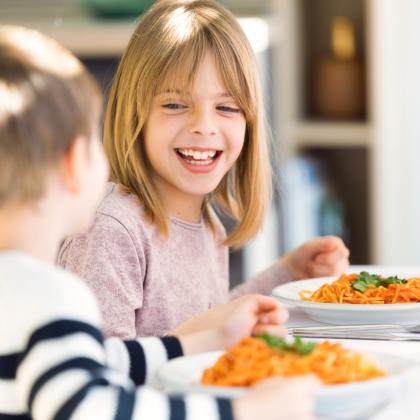 Enfants heureux mangeant des spaghettis ensemble à table.