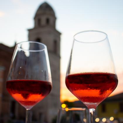Two glasses of red wine at sunset, with a tower in the background.