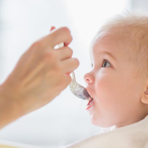 Un bambino viene nutrito con un cucchiaio da una mano adulta.